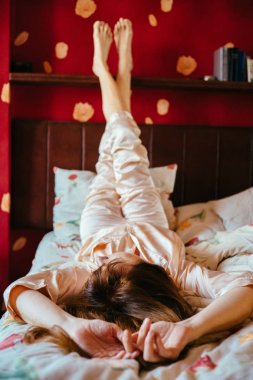 Dikey pijama yatakta kadar ayakları ile rahatlatıcı sevimli genç kadın portresi.