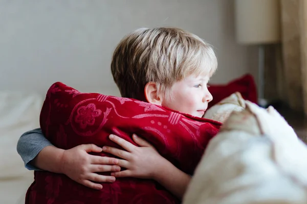 Close up van knappe jongetje een rode kussen te knuffelen en op zoek weg. — Stockfoto