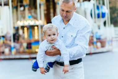 mutlu baba ve oğul atlıkarınca önünde eğleniyor.