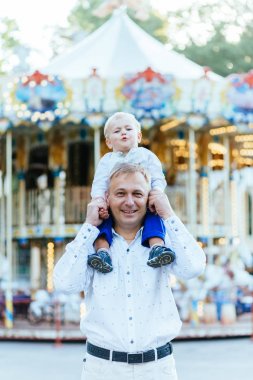 Veren oğlu yolculuk geri amusement park atlıkarınca ile arka plan üzerinde baba