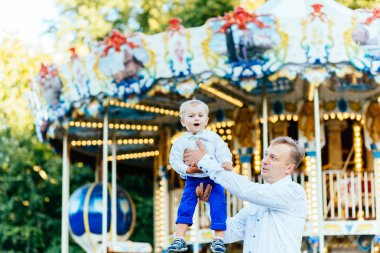 Mutlu baba oğlu atlıkarınca önünde yüksek eğlence parkında atma