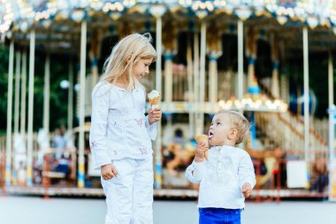 Gülümseyen iki çocuk buz krem ve birbirlerine bakarak yemek