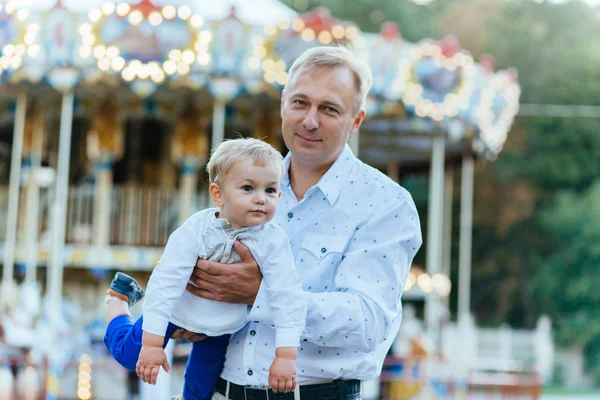 Portre mutlu baba ve oğul önünde atlıkarınca, ellerinde.