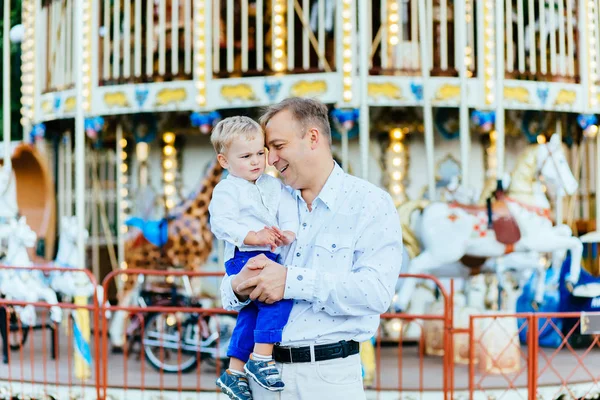 Счастливый отец держит сына в парке развлечений в вечернее время. Концепция дружественной семьи . — стоковое фото