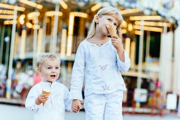 Gülümseyen iki çocuk buz krem ve birbirlerine bakarak yemek