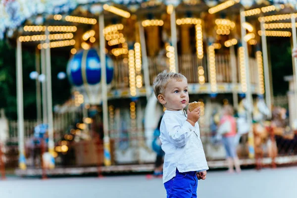 Funny batole boy v bílou košili a modré kalhoty zmrzlina před kolotoč — Stock fotografie