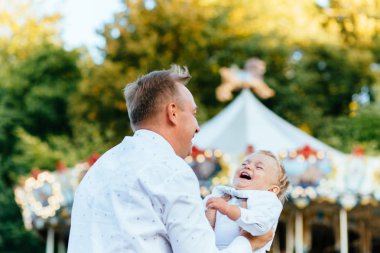 Mutlu baba oğlu atlıkarınca önünde yüksek eğlence parkında atma