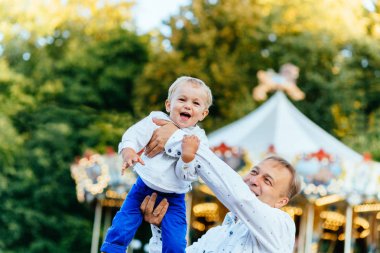 Mutlu baba oğlu atlıkarınca önünde yüksek eğlence parkında atma