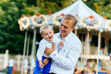 Mutlu baba oğlu atlıkarınca önünde yüksek eğlence parkında atma