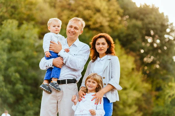 Gelukkige familie van vader, moeder en twee kinderen, baby zoon en dochter in het park van de zomer. — Stockfoto