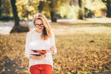 Gözlüklü genç kız öğrencinin kitap okumak ve onu program Sonbahar zaman planlama var. sezon, çalışma, eğitim ve insan kavramı - Güz beyaz kazaklı genç yenilikçi genç kız portresi