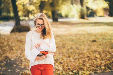Gözlüklü genç kız öğrencinin kitap okumak ve onu program Sonbahar zaman planlama var. sezon, çalışma, eğitim ve insan kavramı - Güz beyaz kazaklı genç yenilikçi genç kız portresi