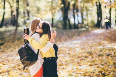 Sarılma, sevindirici ve birbirlerini tebrik samimi kadın gençler okul kızları. Okula dönüş. Eğitim, yaşam tarzı ve insanlar kavramı.