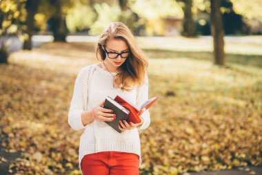 Gözlüklü genç kız öğrencinin kitap okumak ve onu program Sonbahar zaman planlama var. sezon, çalışma, eğitim ve insan kavramı - Güz beyaz kazaklı genç yenilikçi genç kız portresi