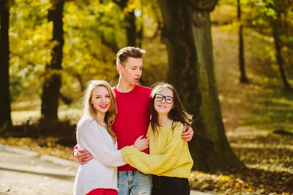 Bir takım üç mutlu arkadaşlar öğrencilerin hugs ve gülüyor bir Avrupa şehri kış Park seyahat kavramı