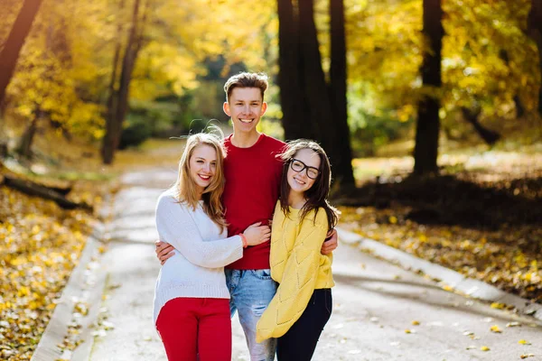 Bir takım üç mutlu arkadaşlar öğrencilerin hugs ve gülüyor bir Avrupa şehri kış Park seyahat kavramı