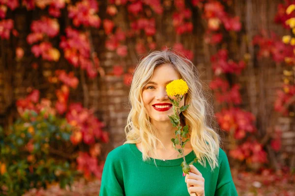 Грайлива позитивна блондинка в зеленому светрі з червоними губами приховує її око — стокове фото