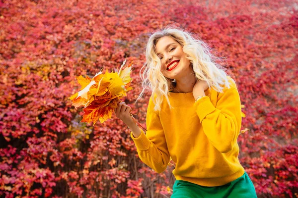 Портрет веселої молодої жінки з осіннім листям перед листям робить селфі — стокове фото