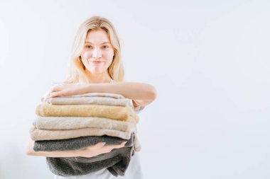 Kadının elinde bir yığın havlu var.
