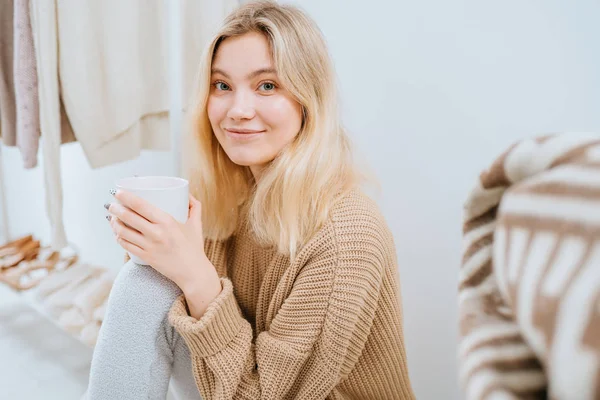 Portret van een leuke blonde huisvrouw op de vloer van Scandinavische stijl, kledingrek in een moderne lichte stijl lege garderobe kamer. Mode blog, website, social media held header sjabloon — Stockfoto