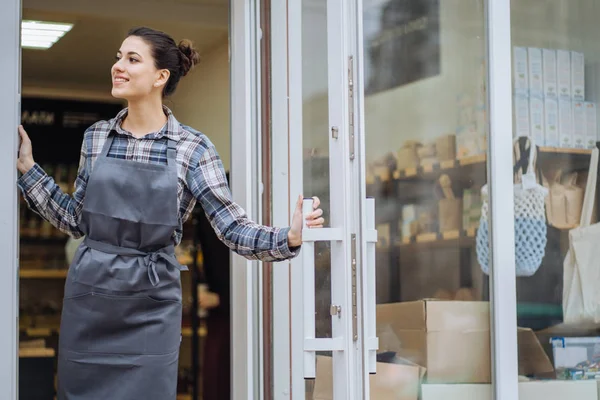 Beautiful asian woman store owner with standing in the doorway of her coffee shop looking at camera and smiling.Portrait of girl waitress wearing apron and standing in front