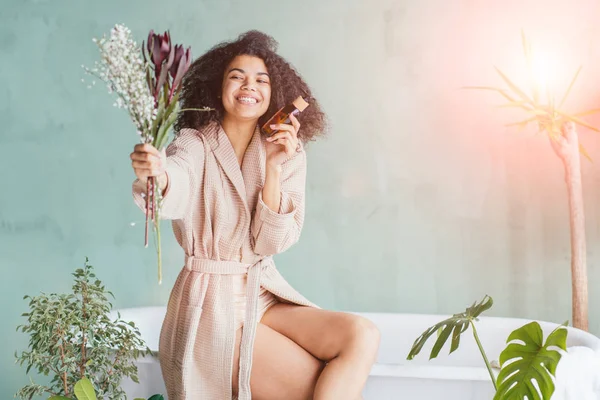 Mulher sorridente com uma garrafa marrom em uma loja natural com produtos orgânicos — Fotografia de Stock