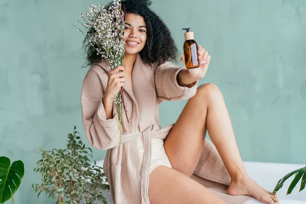 Mulher sorridente com uma garrafa marrom em uma loja natural com produtos orgânicos — Fotografia de Stock