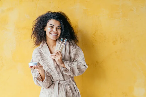 plastic less, zero waste concept, woman holding eco-friendly bamboo toothbrush and natural toothpaste, morning teeth care