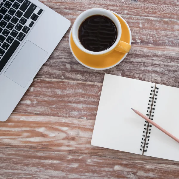 Laptop (notebook) with cup of coffee and notepad with pen on old