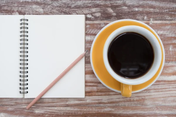 Notepad and coffee cup on wood table. View from above — Stock Photo, Image