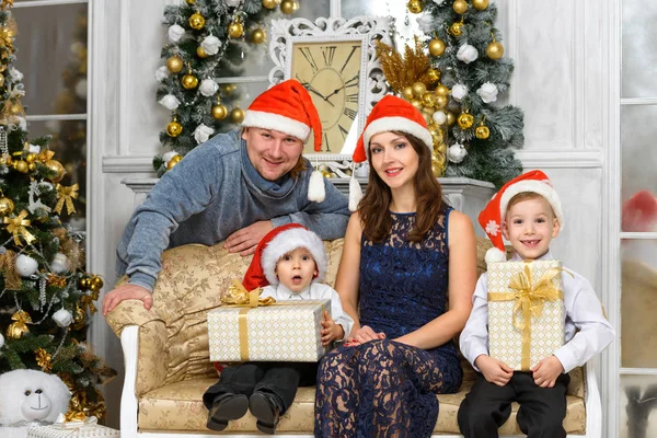 Famille souriante dans santa chapeaux d'aide avec de nombreuses boîtes-cadeaux — Photo