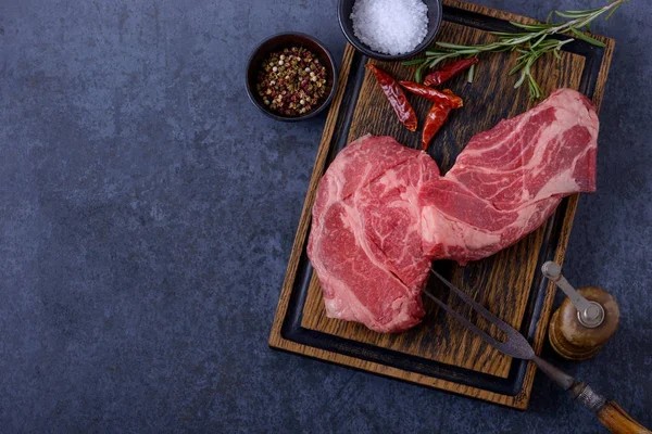 Carne crua, bife com fundo preto e tábua de madeira — Fotografia de Stock