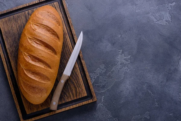 Fresh bread and knife on cutting board — Stock Photo, Image