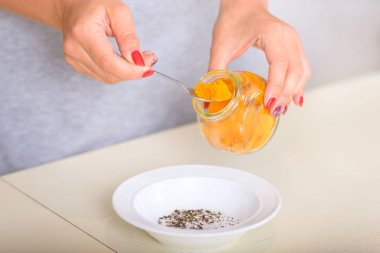 Kadın baharat kaşıkla tutar