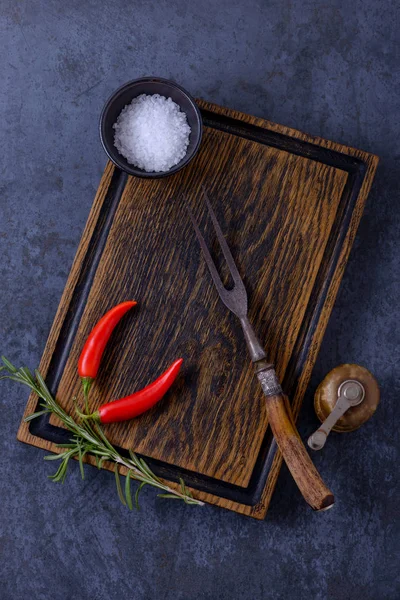 Empty wooden board, pepper shaker and herbs and spices — Stock Photo, Image
