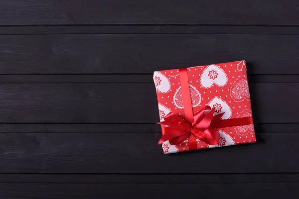 Scatola regalo rossa con cuori su sfondo nero in legno — Foto Stock