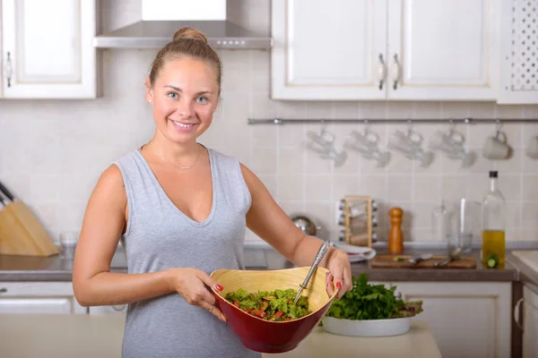 Женщина держит миску с салатом из овощей на кухне — стоковое фото