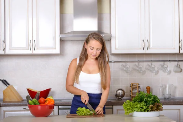 Женщина режет салат на кухне — стоковое фото
