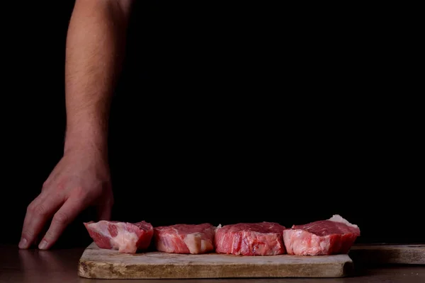 Açougueiro e fatias de carne bovina na tábua de corte — Fotografia de Stock