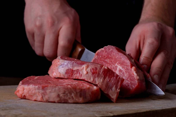 Homem corta carne de vaca na tábua de corte — Fotografia de Stock