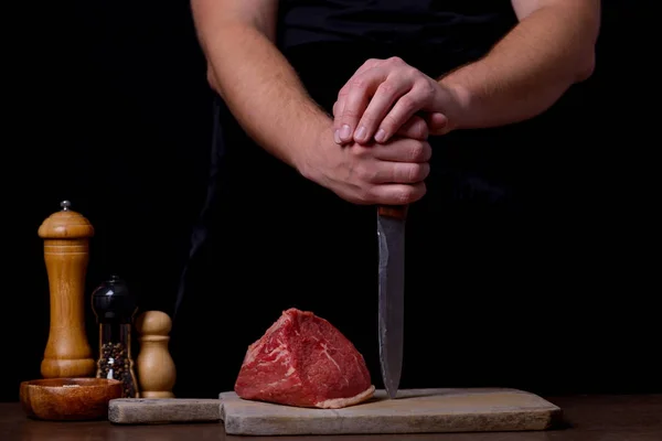 Slager met mes en rauwe biefstuk en specerijen — Stockfoto