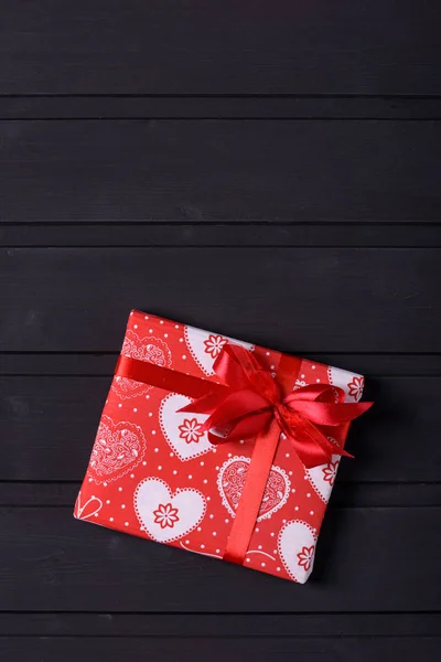 Red gift box with hearts on black wooden background — Stock Photo, Image