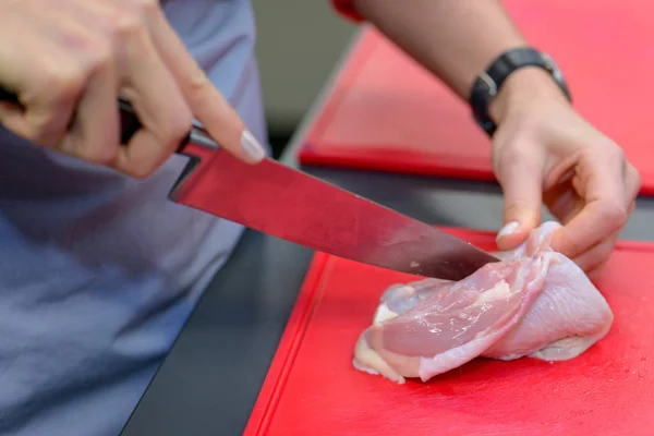 Woman hands cutting chicken meat