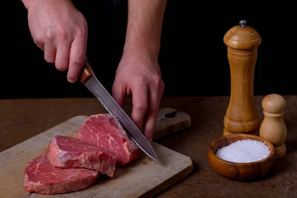 Homem corta carne de vaca na tábua de corte — Fotografia de Stock