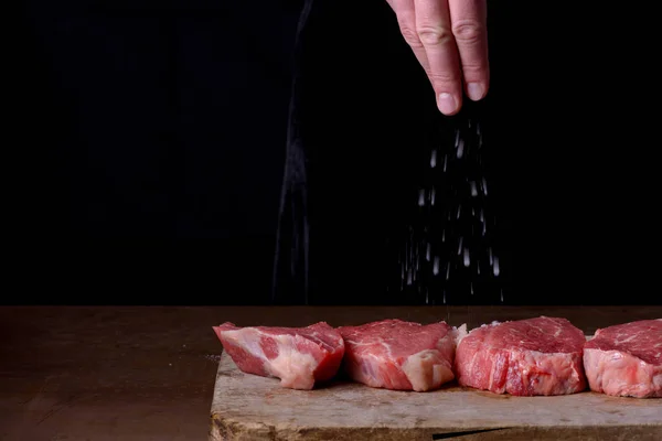 Chef polvilha bifes crus de sal de carne de vaca marmorizada — Fotografia de Stock