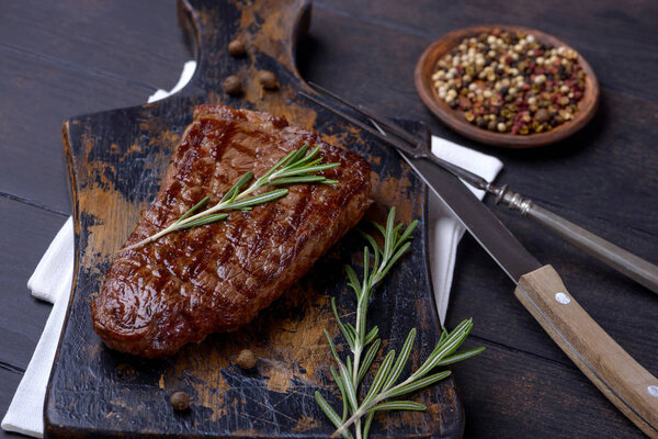 Closeup beef steak and rosemary. Knife and fork for meat