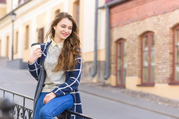 Усміхнена жінка п'є каву на вулиці — стокове фото