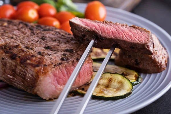 Крупный план нарезанный стейк на тарелке. Мясо и овощи — стоковое фото