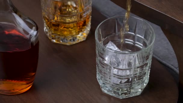 金色のウイスキーやバーボンがグラスに注ぐ ゆっくりとした動きでガラスの中を流れるコニャックやラム ドリンクコンセプト — ストック動画