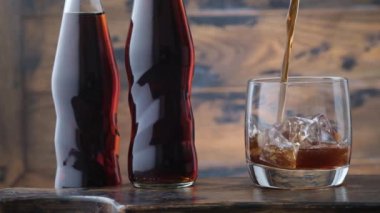 Cama köpüklü limonata döküyorum. Arka planda buz küpleri var. İki şişe. Köpüklü soğuk kola.